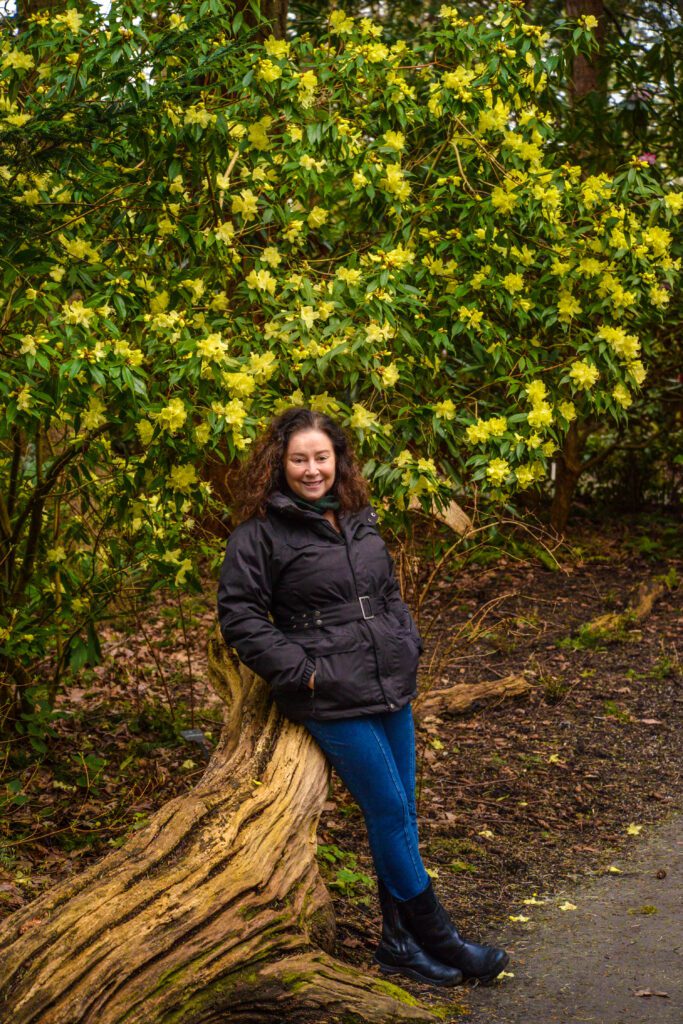 Elizabeth of EV Tours standing among blooming rhododendrons at Finnerty Gardens in Victoria BC