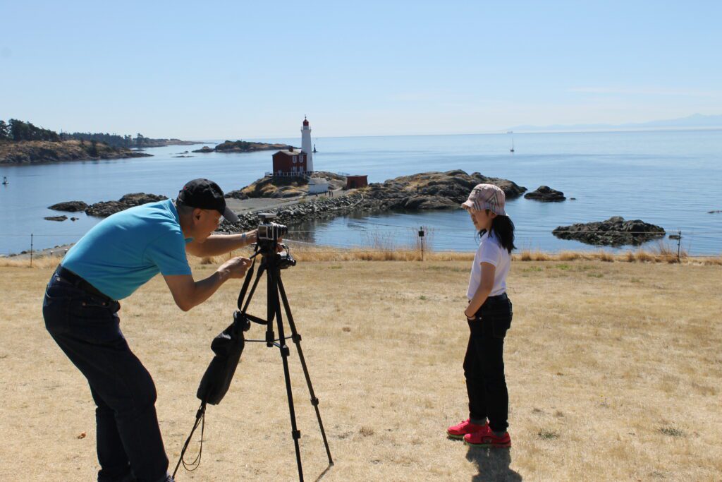 Visitors photographing Fisgard Lighthouse near Victoria BC overlooking the Strait of Juan de Fuca.