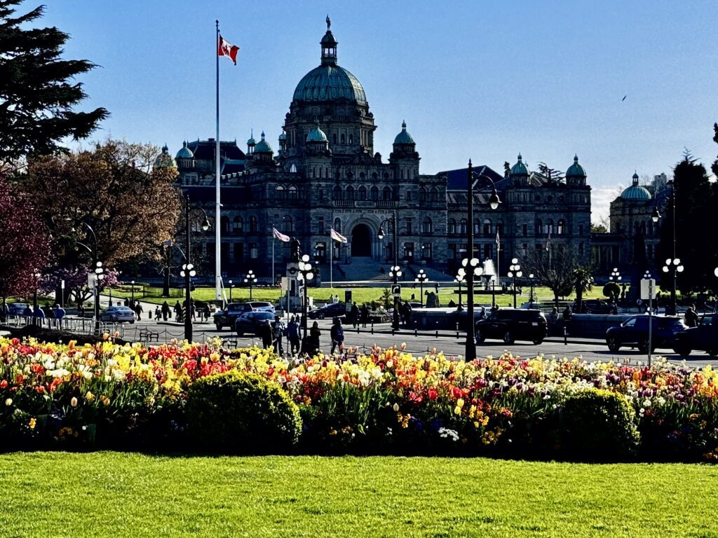 British Columbia Parliament Buildings framed by colourful spring flower beds in Victoria's Inner Harbour.