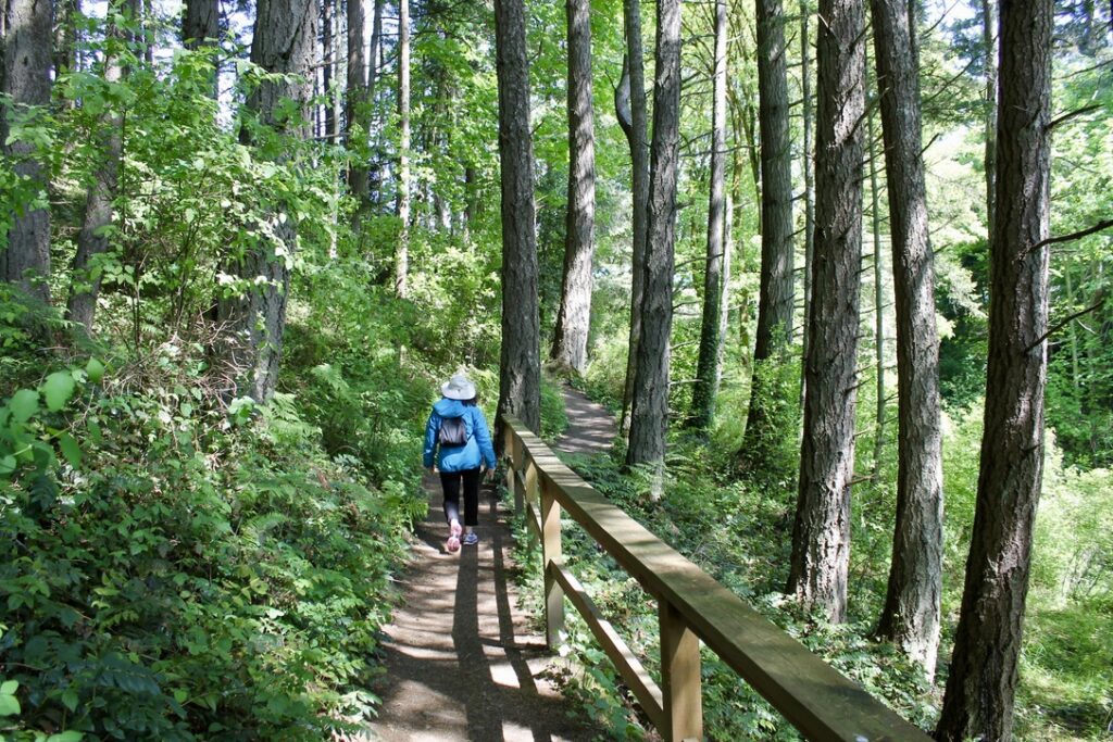 A visitor walking along a wooded trail near Hatley Castle in Victoria, British Columbia.